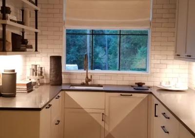 A kitchen with white cabinets and a window.